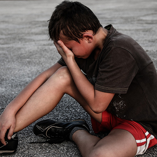 Young man seated and crying with his hand over his face