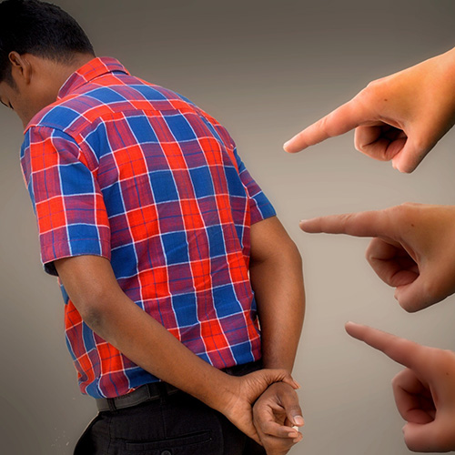 Three hands with fingers pointed at a young man with his back to them