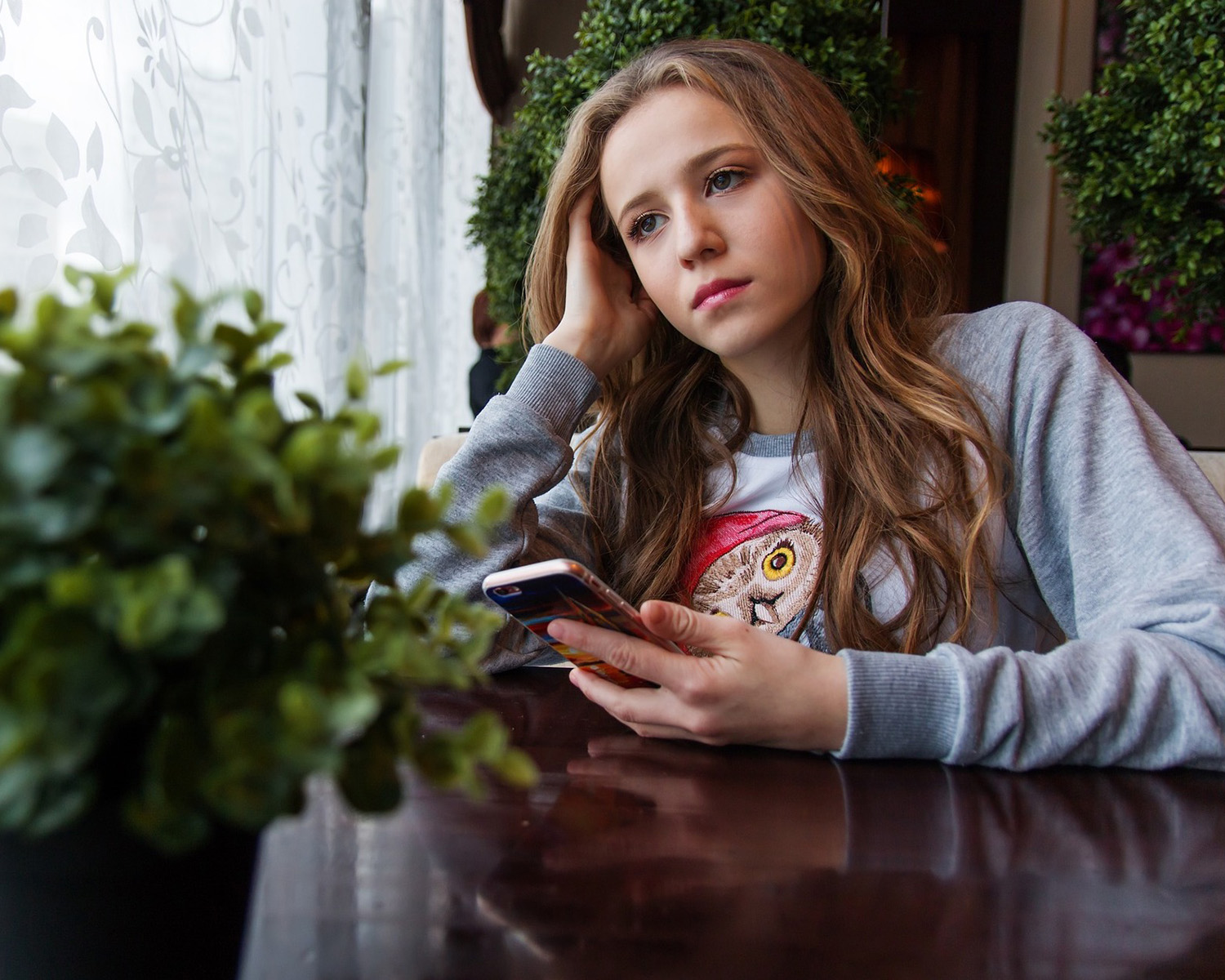 Girl sitting at a table on her cell phone