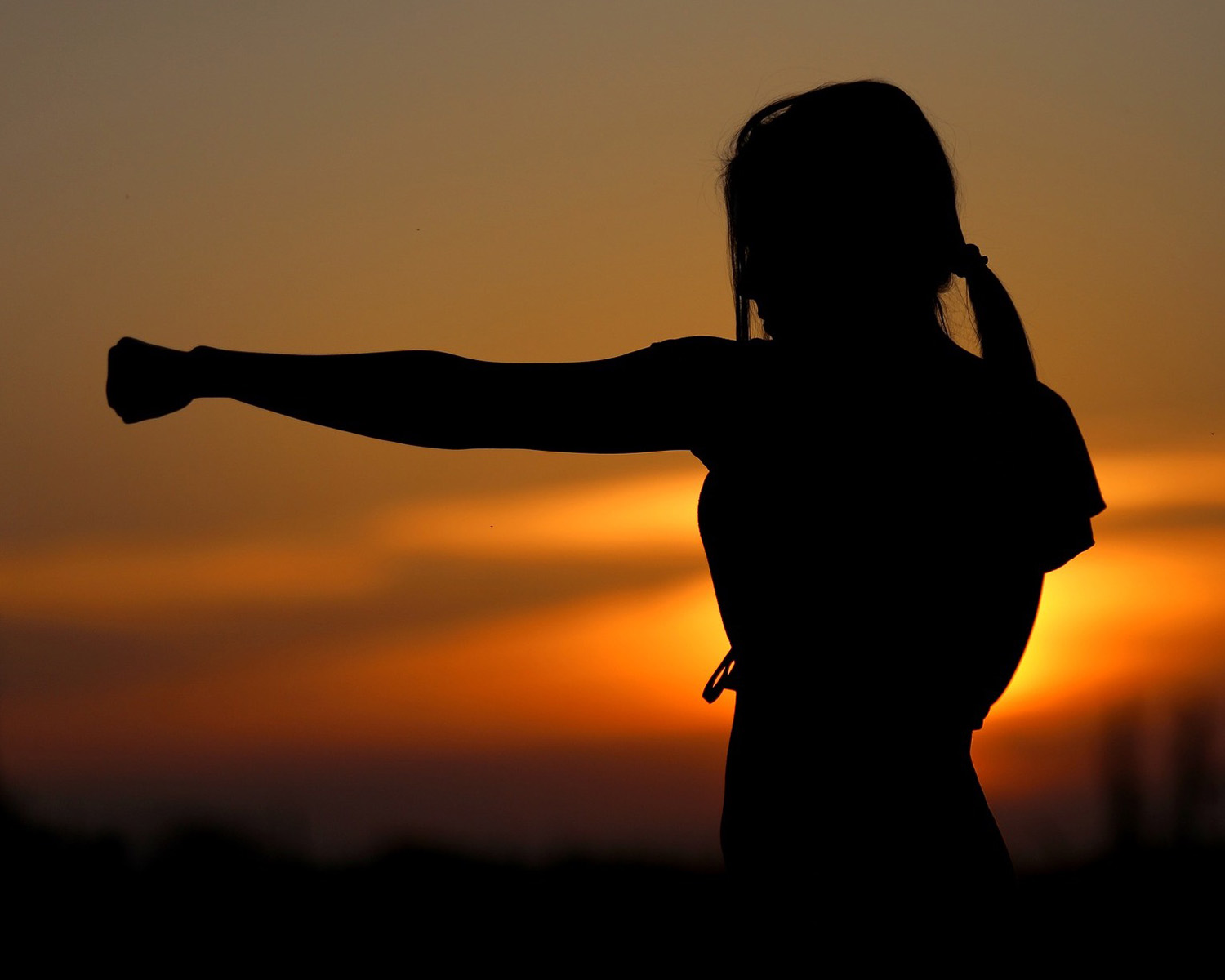 Female figure practicing punches during sunset