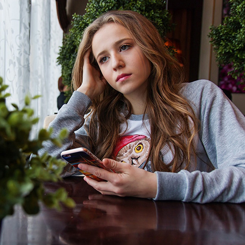Girl sitting at a table on her cell phone